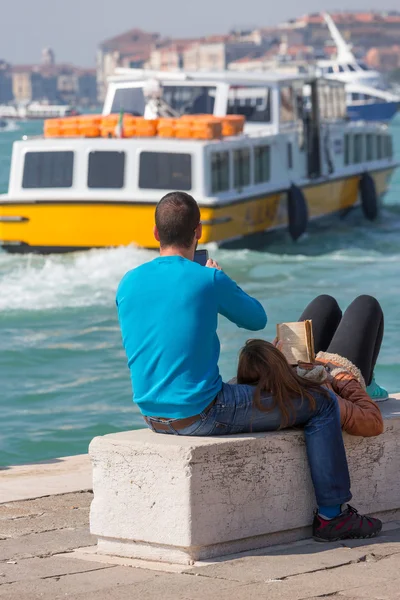 Young lovers lying on a bench in front of the Venice lagoon — Stock Photo, Image