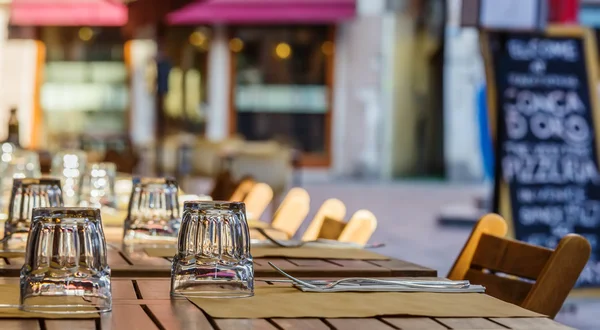 Restaurant tabel met glazen en menu in de achtergrond — Stockfoto