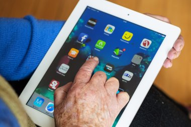 Paris, Fev 2016 - Bir ipad ekranda birçok uygulama ile tablet kullanan kıdemli kadın