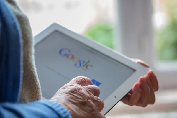 Париж, Франция - 27 апреля 2015 г.: Старшая женщина, использующая планшет с поисковой страницей Google на экране ipad — стоковое фото