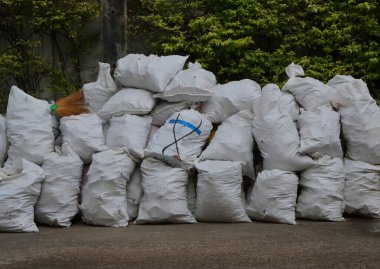 Çöp yığını atık alanındaki beyaz çuvallarda saklanıyor, atık sıralaması geri dönüşüm için bekliyor.