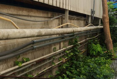 Bahçedeki duvara bağlı elektrik kabloları yerleştirilmiş. Sarı boru kıvrımlı.