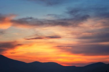 Gün batımında parlak gökyüzünün arka planı. Dağ siluetleri.