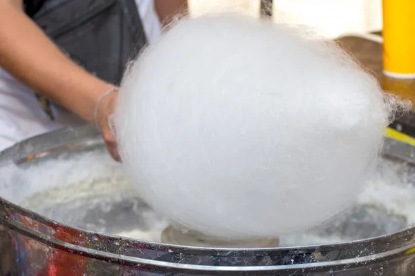Hand rolling white cotton candy in candy floss machine. Sweets for children.