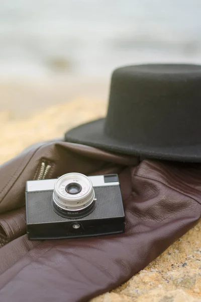 老式摄影相机和黑色的帽子在石头上 旅行概念的背景 — 图库照片