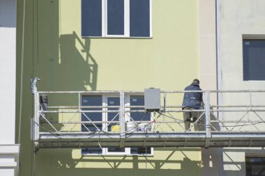 Çok katlı bir binanın inşaatı. İnşaat alanındaki bir evin duvarını sıva yapan bir işçi..