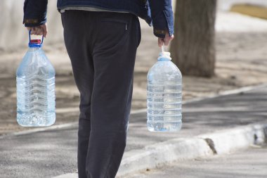 Mykolayiv, Ukrayna - 14 Nisan 2020: şişe su taşıyan adam. Kentsel alanlarda doğal içme suyu sağlanması.