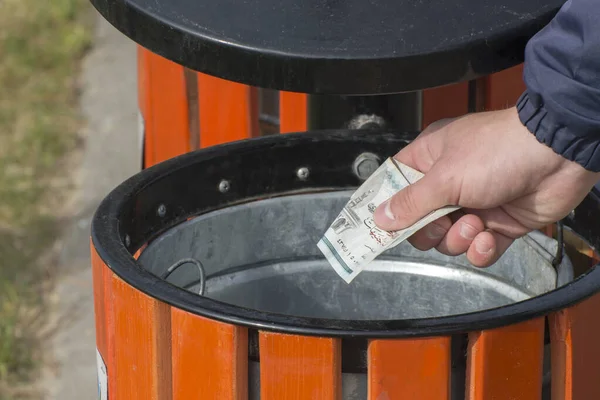 A man throws a bill into the trash can. Conceptual photo. Money supply inflation, financial crisis. Waste of money.