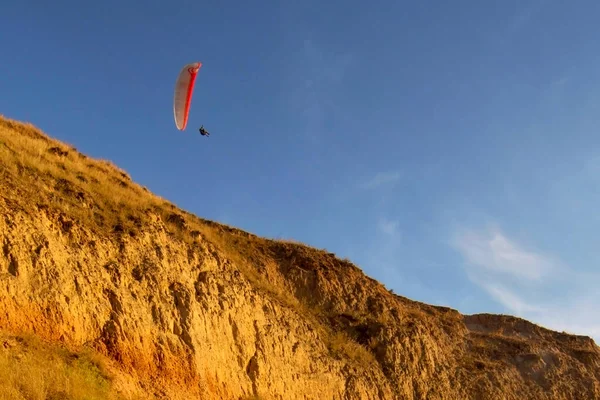 Mavi gökyüzüne karşı bir paraglider ile manzara. Dağlar, günbatımı ve gökyüzünde yamaç paraşütü.