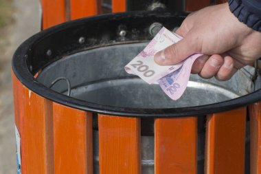 Ulusal para birimi enflasyonu. Adamın biri çöp kutusuna para atıyor..