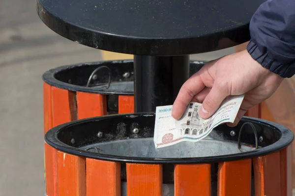 National currency inflation. A man throws a banknote into a trash can. Donation of money.