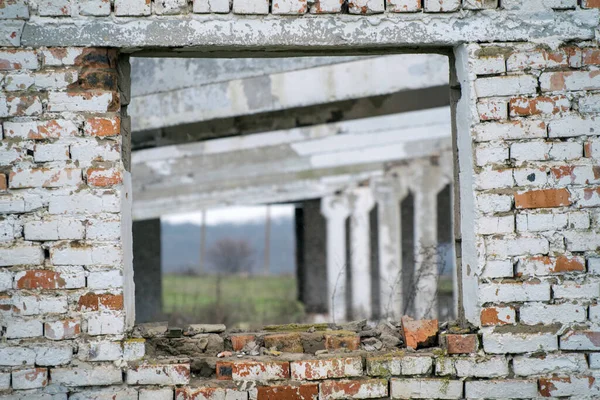 Broken window in the wall of the house. Industrial ruins and old brick walls close-up. Specially defocused photo.