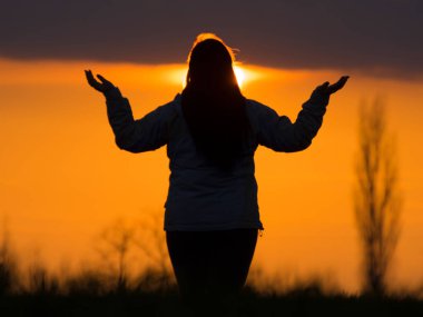 Batan güneşe karşı meditasyon yapan genç bir kadının silueti. Özel olarak odaklanmış fotoğraf.