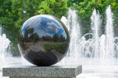 Şehir parkında granit top. Gökyüzünün ve bulutların güzel yansıması. Çeşme. Şehir manzarası.
