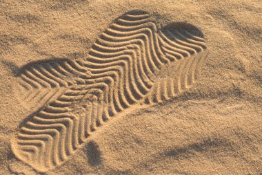 Two footmarks in the sand. Beautiful sand background with geometric pattern. Travel stop abstraction. Selective focus.