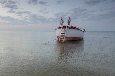 Deniz kıyısında bir balıkçı teknesi. Sabahın erken saatlerinde, sakin su.