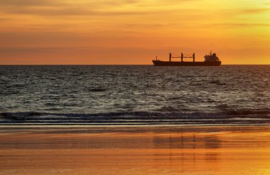 Gün batımında okyanusa kargo gemileri