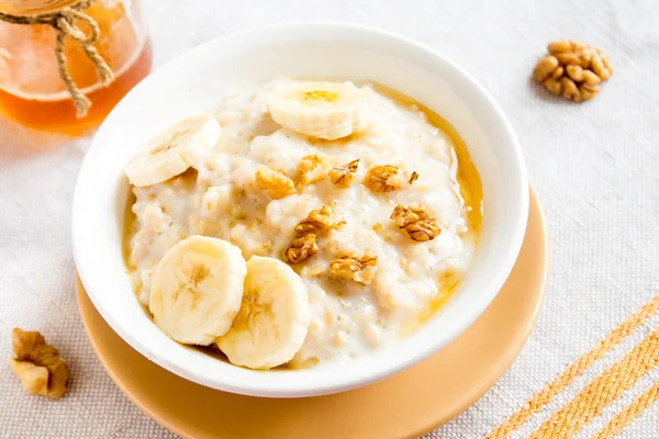 Oatmeal porridge with banana, nuts and honey — Stock Photo, Image