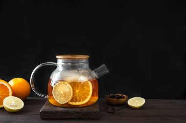 Limonlu citrus çayı, modern cam çaydanlıkta portakallar koyu ahşap masada, kopyalama alanı. Meyve çayı. Mevsimlik kış mevsimi sıcak sonbahar içeceği.