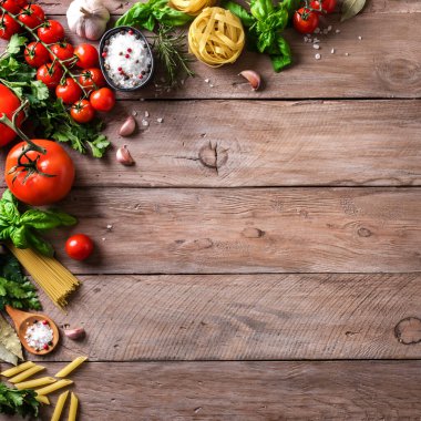 Sebzeler ve pişirilmemiş makarna, aşçılık arka planı, üst manzara, fotokopi alanı. Çeşitli İtalyan makarnaları, domatesler, fesleğen ve baharatlar, İtalyan mutfağı konsepti..