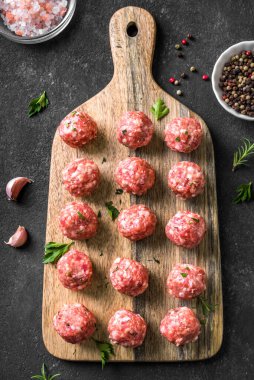 Siyah arkaplanda çiğ köfteler, üst görünüm, kopyalama alanı. Tahtada köfteler pişmeye hazır..