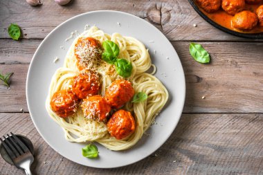 Köfteli spagetti makarna, domates sosu rendelenmiş peynir ve taze fesleğen - sade ahşap arka planda ev yapımı italyan makarnası, üst manzara, kopyalama alanı..