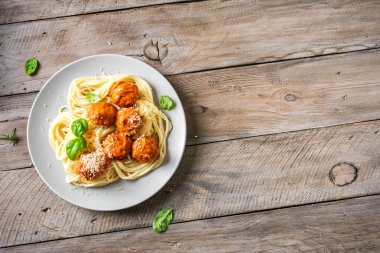 Köfteli spagetti makarna, domates sosu rendelenmiş peynir ve taze fesleğen - sade ahşap arka planda ev yapımı italyan makarnası, üst manzara, kopyalama alanı..