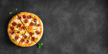 Büyük Pepperoni ve Mozzarella pizzası siyah masada, üst manzara, kopyalama alanı. Nefis taze pişmiş pizza..
