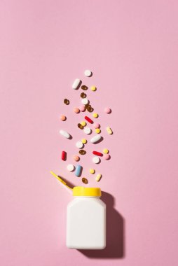 Çok renkli tabletler, haplar, plastik kapsüller pembe arka planda, kopyalama alanı. Çeşitli ilaç tabletleri ve haplar, vitamin ve besin takviyeleri konsepti..