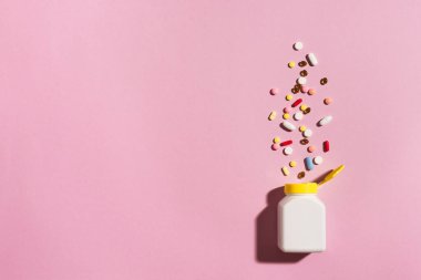Çok renkli tabletler, haplar, plastik kapsüller pembe arka planda, kopyalama alanı. Çeşitli ilaç tabletleri ve haplar, vitamin ve besin takviyeleri konsepti..