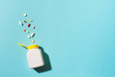 Çok renkli tabletler, haplar, plastik kapsüller mavi arka planda, kopyalama alanı. Çeşitli ilaç tabletleri ve haplar, vitamin ve besin takviyeleri konsepti..