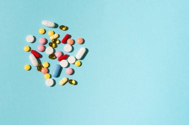 Çok renkli tabletler, haplar, mavi arka planda kapsüller, kopyalama alanı. Çeşitli ilaç tabletleri ve haplar, vitamin ve besin takviyeleri konsepti..