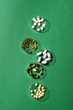 Yeşil zemin üzerinde vitamin kapsülleri, üst görünüm, kopyalama alanı. Besin takviyeleri: balık yağı, omega 3, omega 6, omega 9, A vitamini, D3, E, B, kalsiyum.