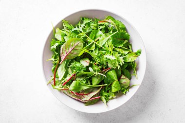 Sağlıklı yeşil salata, taze organik yapraklar roka ile karıştırılmış salata, İsviçre pazısı ve marul beyaz arka planda, üst manzara, kopyalama alanı.