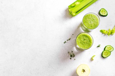Yeşil sebze suyu ya da bardakta meyve suyu. Taze sıkılmış detoks yeşil meyve suyu ve bir demet organik kereviz, salatalık, beyaz masada elma, üst manzara, kopyalama alanı.