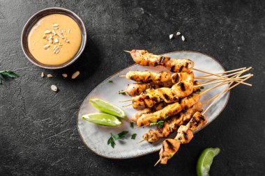 Limon ve fıstık sosuyla servis edilen tavuk ızgara satay şiş. Asya Tayland tarzı yemekler..