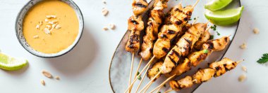 Limon, fıstık sosu ve pankartla servis edilen tavuk ızgara satay şiş. Asya Tayland tarzı yemekler..