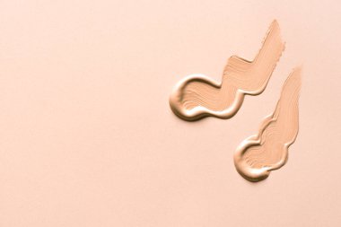 Bej arka planda sıvı makyaj malzemesi. cc, bb kremi, düzeltici ya da sıvı temel krem smear örneği.