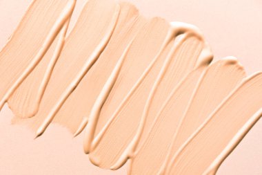 Sıvı taban ya da pansiyon kremi dokusu yakın. Bej renk düzeltici, kapatıcı, temel lekeli fırça darbeleri.