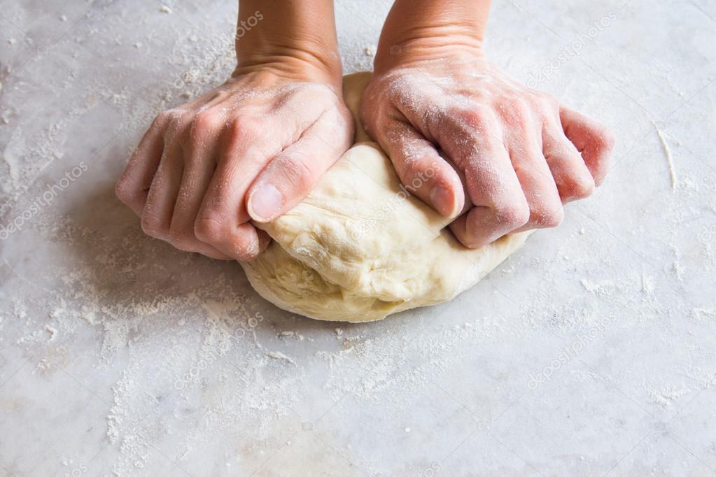 Hands knead dough