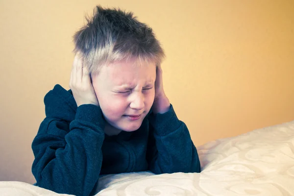 Pojke med ögonen stängda som täcker öronen med händer — Stockfoto