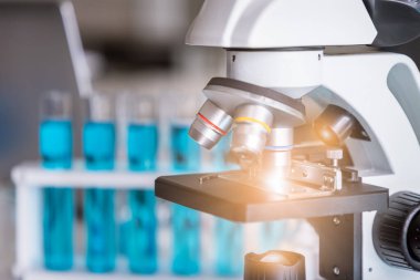 Arka planda test tüpleri olan mikroskop inceleme slaytı yakın plan. Laboratuvarda bilim ve teknoloji araştırması kavramı.