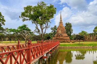 Gölün karşısındaki kırmızı ahşap köprü pagoda ve Wat Sa Si tapınağındaki harabe manastır kompleksi, Sukhothai Tarih Parkı, Tayland