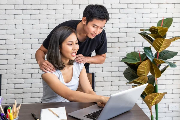 Asyalı koca, evde çalışan, oturma odasında masa başında yemek yiyen bir kadını destekliyor.