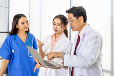 Asyalı erkek ve kadın tıp doktoru ekibi dizüstü bilgisayarla aşıyı tartışıyor ve tartışıyorlar.