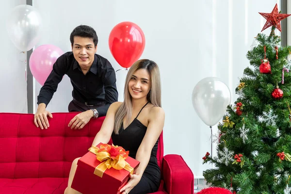 魅力的な若いカップルは一緒にクリスマスと新年を祝います 女性にプレゼントボックスを与える男 — ストック写真