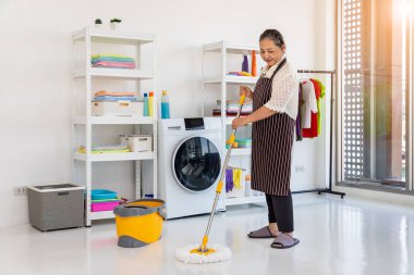 Mutlu Asyalı son sınıf bayan paspas kullanarak yerleri temizliyor.