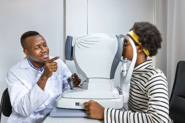 Klinikte ya da optik dükkanda otomatik fraktör kullanarak göz testi yapan Afrikalı genç bir kız. Göz konsepti.