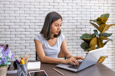 Evde çalışan, oturma odasındaki masa başında yemek yiyen Asyalı kadın portresi.