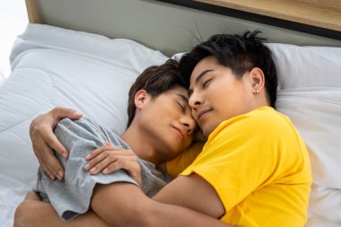 Mutlu Asyalı homoseksüel erkek eşcinsel çift yatakta uzanıyor ve sarılıyorlar, birlikte yatıyorlar. LGBT ve cinsel çeşitlilik kavramı.